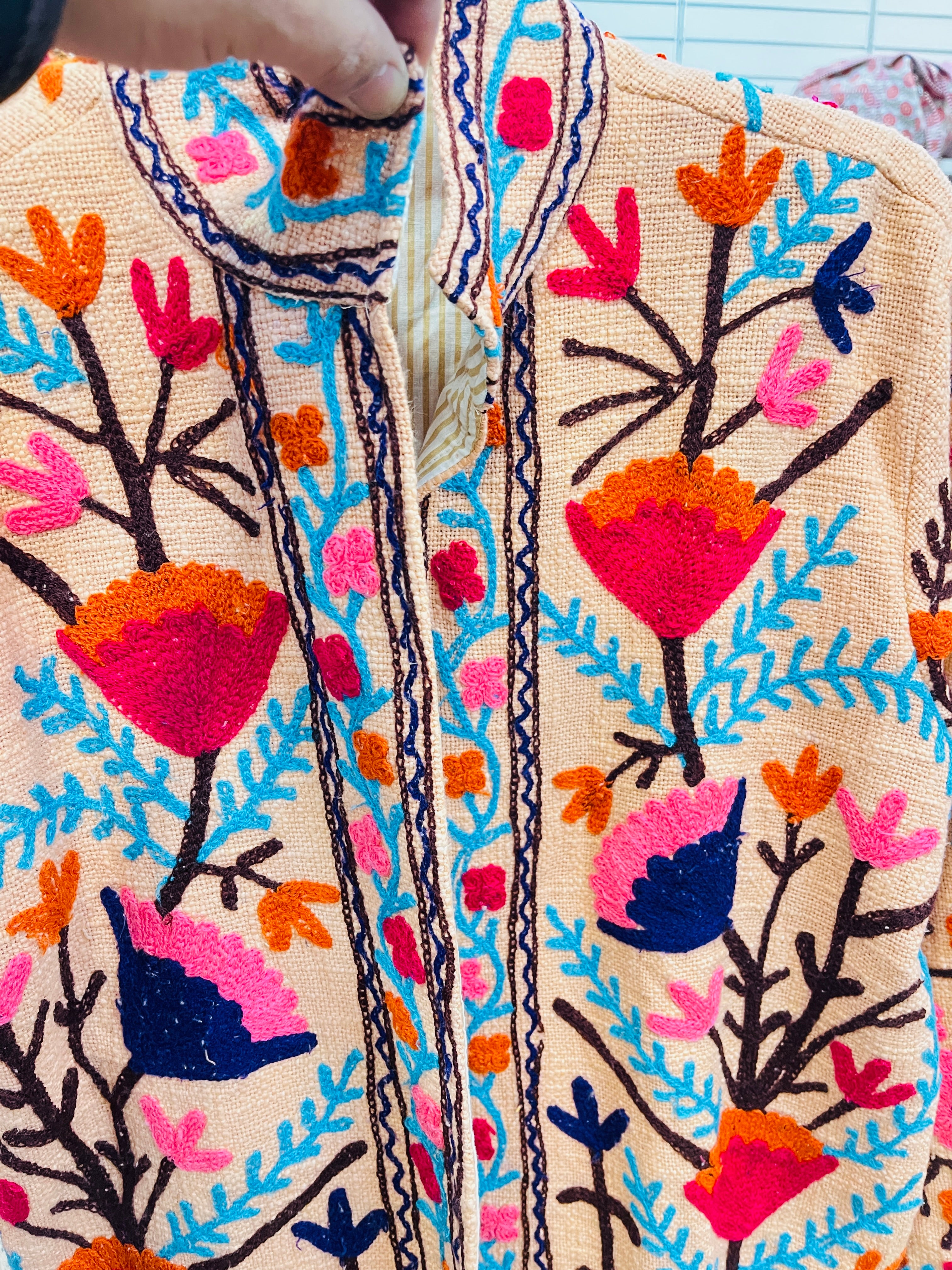 Suzani embroidered jacket detail - close-up of colorful embroidery work on cotton fabric
